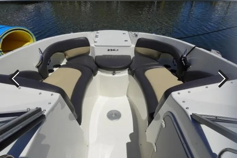 Slide: The Image of 2018 Stingray 234 LR boat interior with cushioned seating and water view. - 5