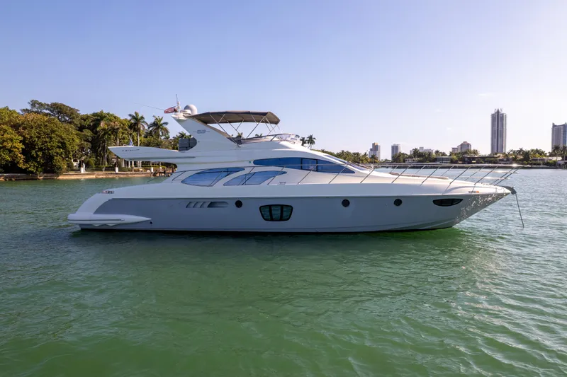 The Image of 2008 Azimut 62E yacht cruising on calm waters near a city skyline. - 0