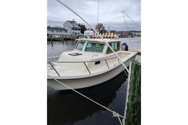 The Image of 2004 Parker 2520 XL Sport Cabin boat docked at a marina on a cloudy day. - 0