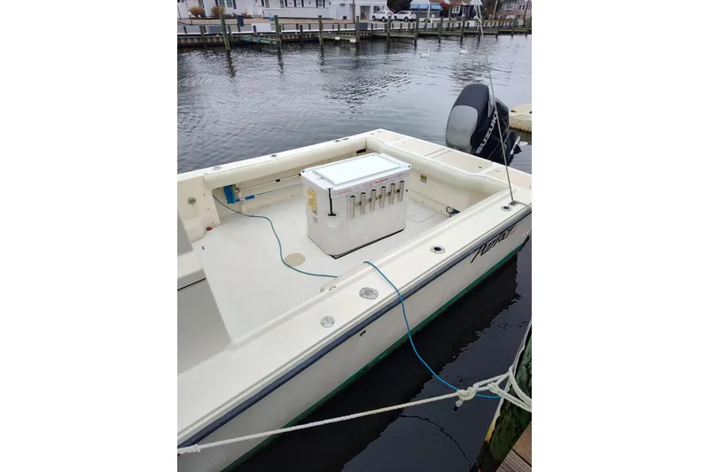 Slide: The Image of 2004 Parker 2520 XL Sport Cabin boat docked, featuring spacious deck and outboard motor. - 2