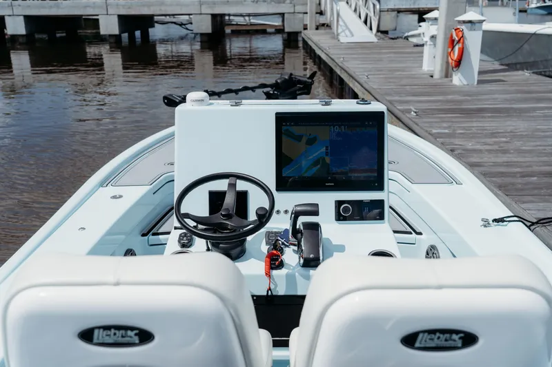Slide: The Image of 2025 East Cape 25 Hybrid boat dashboard with steering wheel and navigation screen at dock. - 6