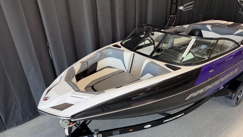 Slide: The Image of A 2016 Moomba Mojo boat with a purple and black design, displayed in a showroom. - 4
