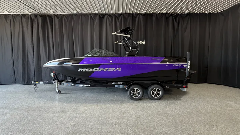 Slide: The Image of 2016 Moomba Mojo boat with a black and purple hull on a trailer. - 0