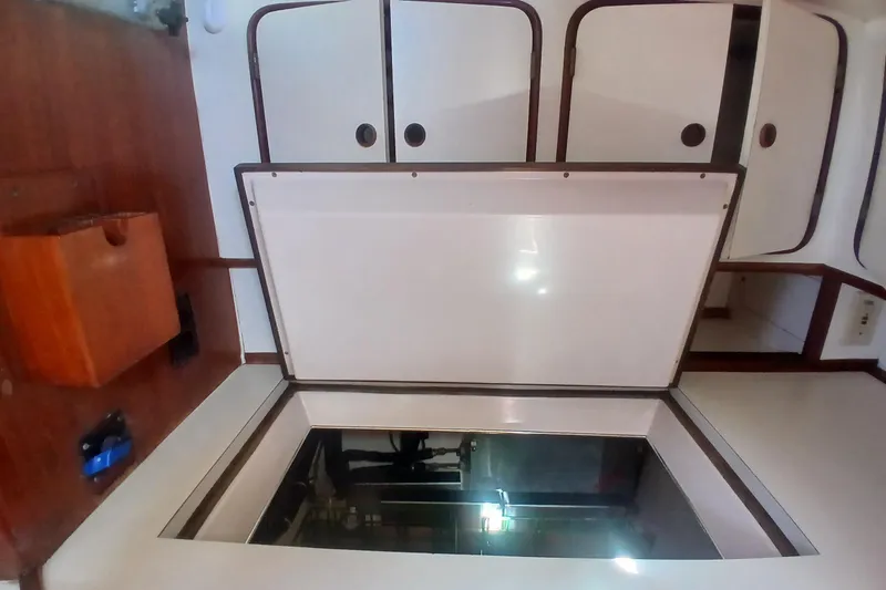 Slide: The Image of Engine compartment access on a 1981 Gulfstar 44 sailboat, featuring white cabinetry and wood accents. - 10