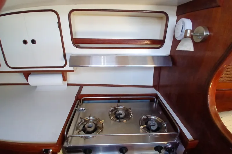 Slide: The Image of 1981 Gulfstar 44 yacht kitchen with stove, wooden cabinetry, and storage shelves. - 14