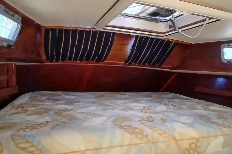 Slide: The Image of Cozy cabin interior of 1981 Gulfstar 44 sailboat with wood paneling and patterned bedding. - 21