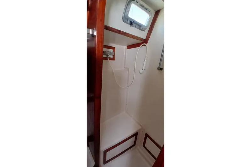 Slide: The Image of Interior shower area of a 1981 Gulfstar 44 yacht, featuring wooden trim and a porthole. - 32