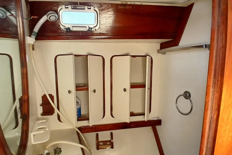 Slide: The Image of 1981 Gulfstar 44 yacht bathroom with wooden cabinets and porthole window. - 34