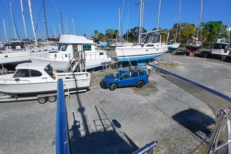 Slide: The Image of Boats and a blue SUV parked in a marina, featuring a 1981 Gulfstar 44 sailboat. - 49