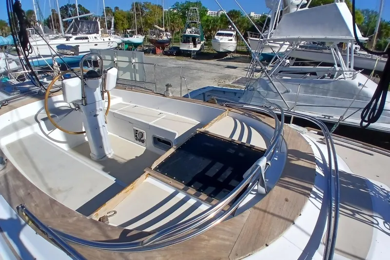 Slide: The Image of 1981 Gulfstar 44 sailboat cockpit with steering wheel, docked among other boats. - 52
