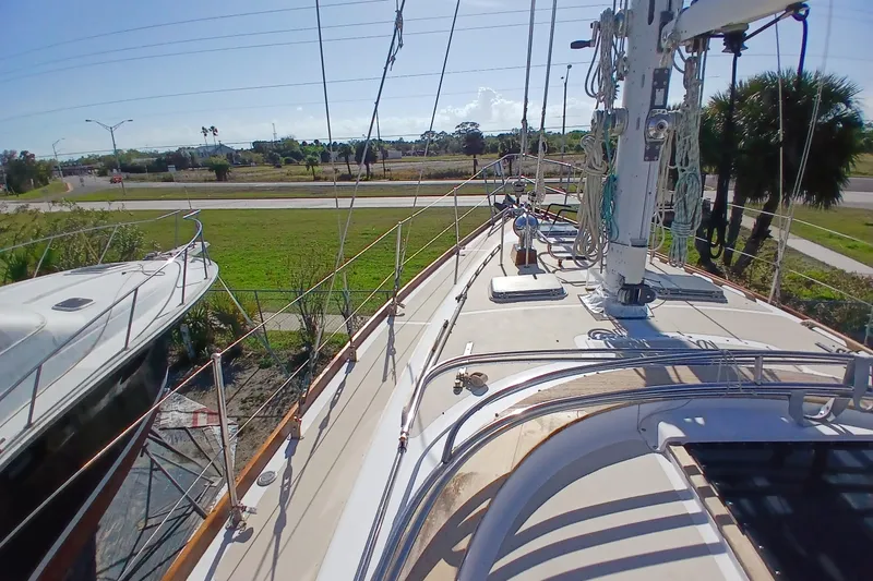 Slide: The Image of 1981 Gulfstar 44 sailboat deck with rigging, docked near a grassy area and road. - 54