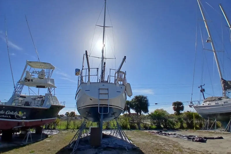 Slide: The Image of 1981 Gulfstar 44 sailboat on land, surrounded by other boats, under a clear blue sky. - 63