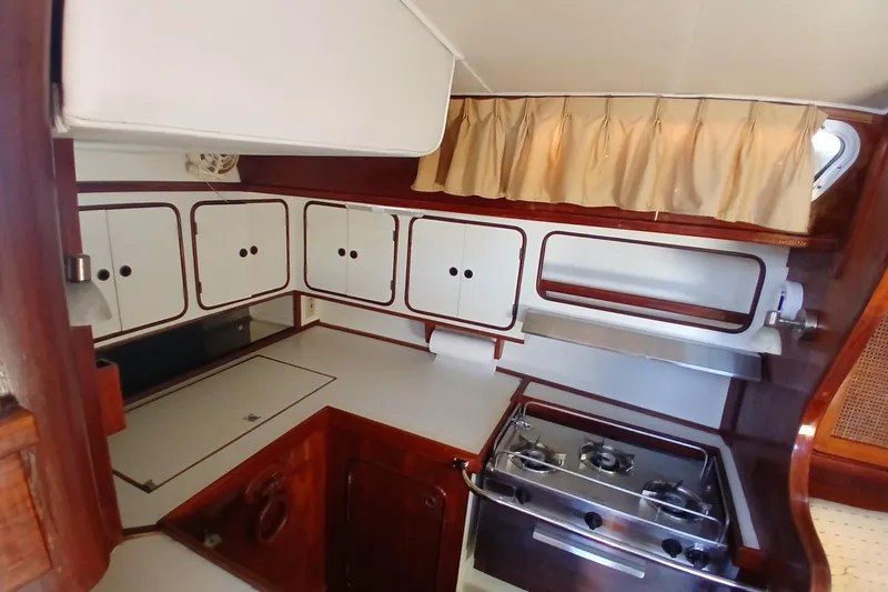 Slide: The Image of 1981 Gulfstar 44 yacht kitchen with stove, cabinets, and curtains. - 8