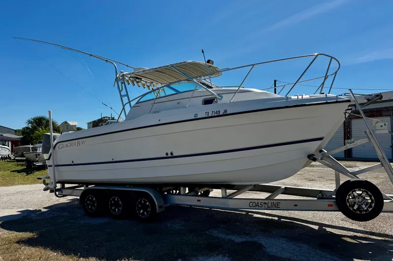 The Image of 2000 Glacier Bay 2670 Isle Runner boat on trailer under clear blue sky. - 0
