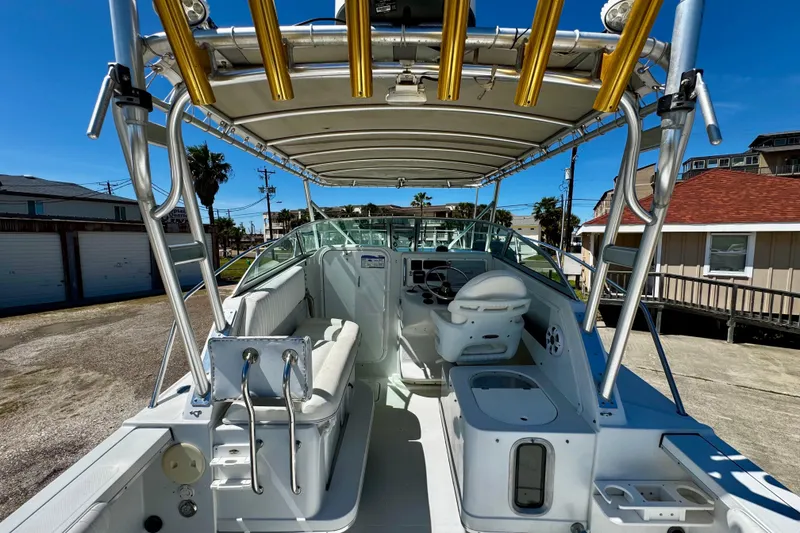 Slide: The Image of 2000 Glacier Bay 2670 Isle Runner boat interior with seating and helm, docked under clear sky. - 18