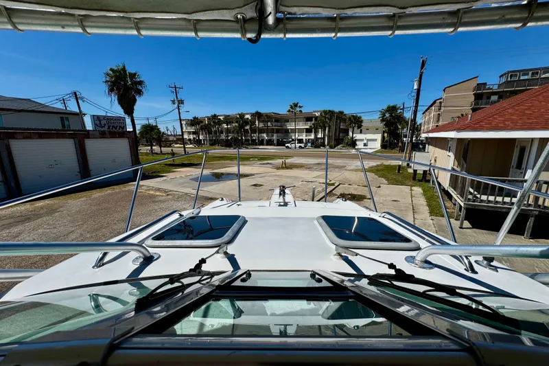 Slide: The Image of 2000 Glacier Bay 2670 Isle Runner boat docked near coastal buildings under clear blue sky. - 19