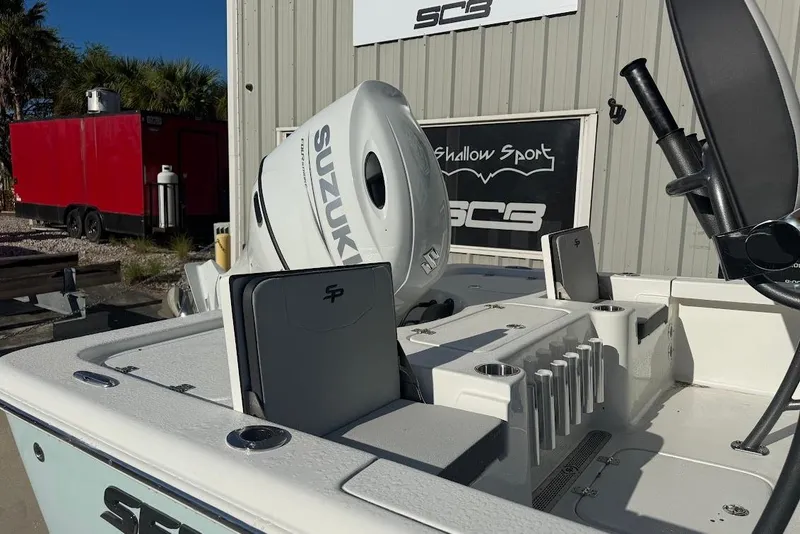 Slide: The Image of 2026 Sea Pro 210 Bay boat with Suzuki engine, docked near a red trailer. - 2