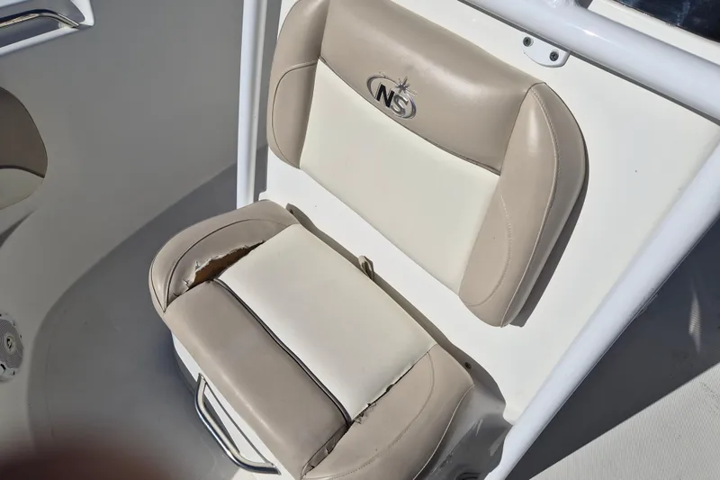 Slide: The Image of 2017 NauticStar 2102 Legacy boat seat with beige and white upholstery, showing wear. - 12