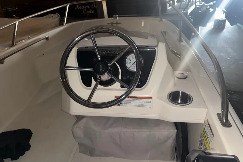 Slide: The Image of 2022 Boston Whaler 130 Super Sport boat dashboard with steering wheel and gauge. - 2