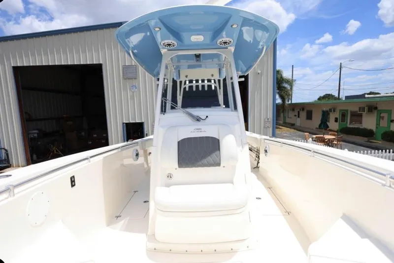Slide: The Image of 2022 Cobia 301 Center Console boat with blue T-top, docked near buildings. - 12