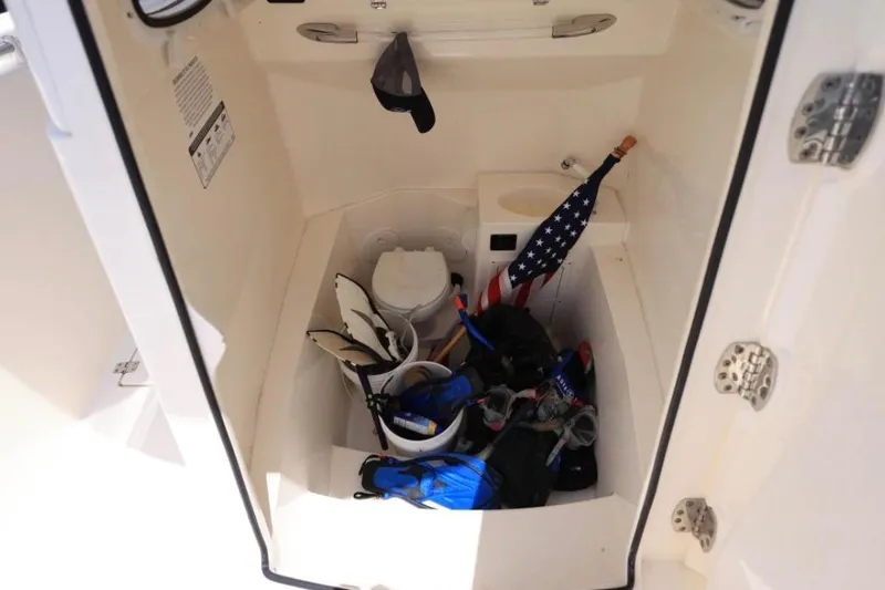Slide: The Image of Storage compartment of 2022 Cobia 301 Center Console with gear and American flag. - 13