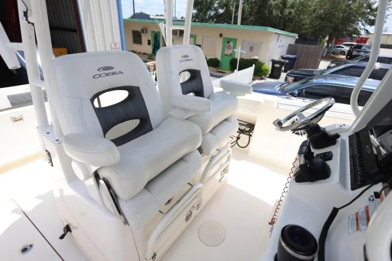 Slide: The Image of 2022 Cobia 301 Center Console boat interior with dual captain's chairs and steering console. - 14