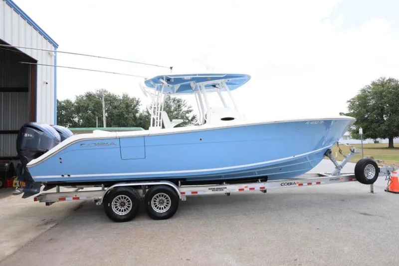 Slide: The Image of 2022 Cobia 301 Center Console boat on trailer, parked outside a building. - 18