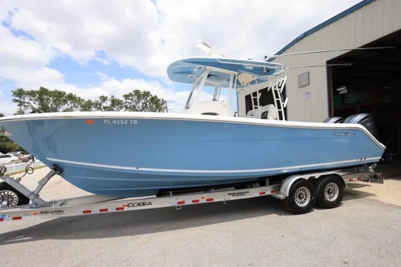 Slide: The Image of 2022 Cobia 301 Center Console boat on trailer, parked outside a building. - 19