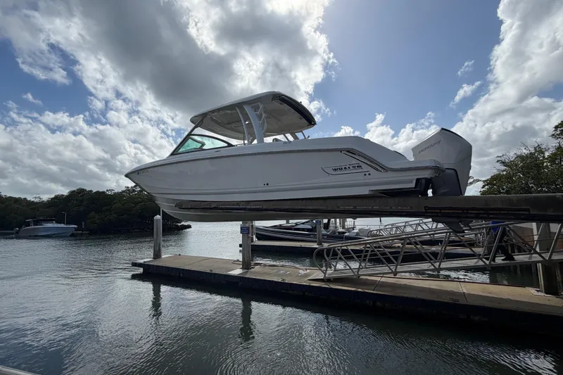 Slide: The Image of 2022 Boston Whaler 320 Vantage boat on lift by waterfront under cloudy sky. - 10