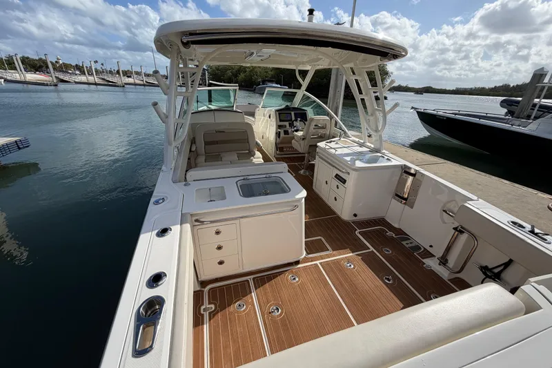 Slide: The Image of 2022 Boston Whaler 320 Vantage boat interior with seating and helm, docked by the water. - 17