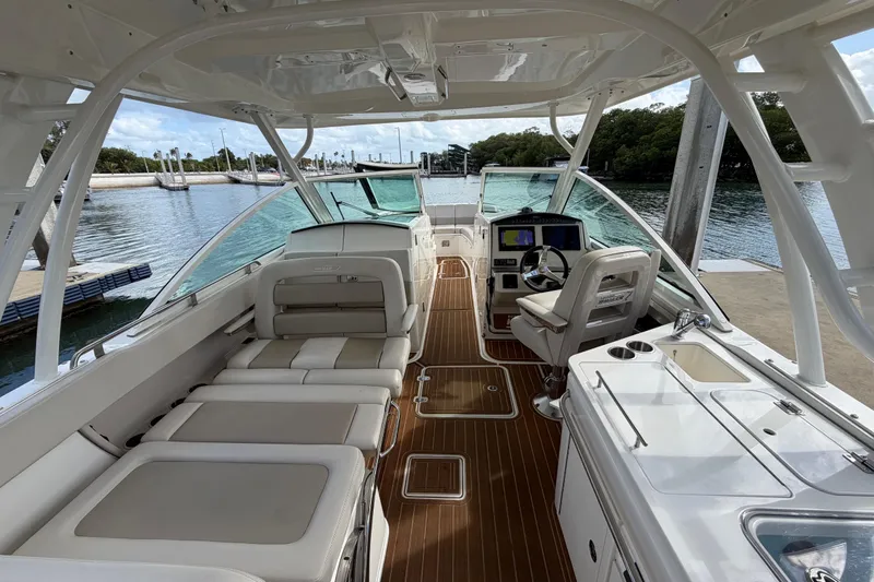 Slide: The Image of 2022 Boston Whaler 320 Vantage boat interior with seating and helm, docked by the water. - 18