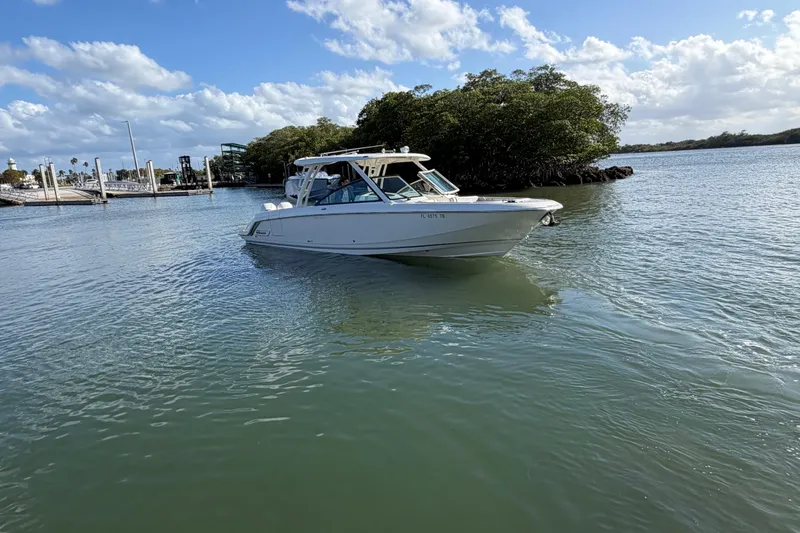Slide: The Image of 2022 Boston Whaler 320 Vantage boat cruising on a sunny day near a marina. - 2