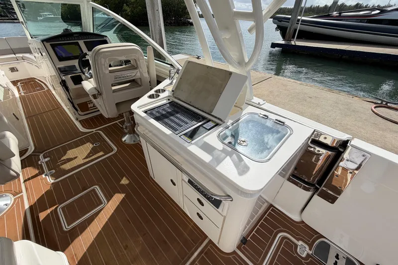 Slide: The Image of 2022 Boston Whaler 320 Vantage boat interior with helm, seating, and kitchenette by the water. - 24
