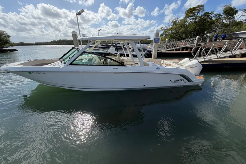 Slide: The Image of 2022 Boston Whaler 320 Vantage boat docked in a scenic marina. - 5