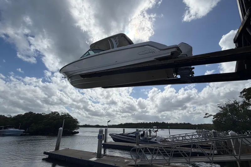 Slide: The Image of 2022 Boston Whaler 320 Vantage boat lifted at marina under cloudy sky. - 9