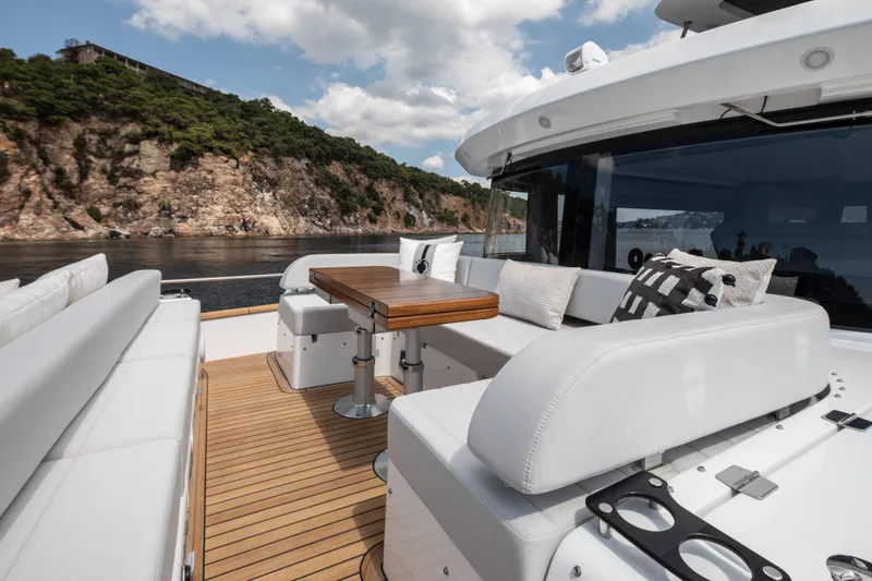 Slide: The Image of Luxurious Sirena 60 yacht deck with elegant seating, wooden table, and scenic coastal view, 2026 model. - 18