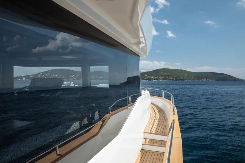 Slide: The Image of Luxurious Sirena 60 yacht cruising on open sea, reflecting scenic coastal landscape, 2026 model. - 20