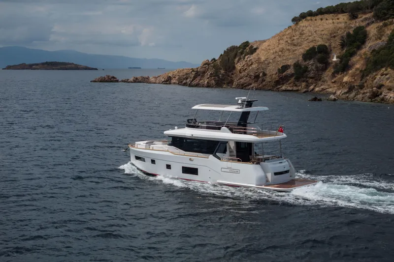 Slide: The Image of Luxurious 2026 Sirena 60 yacht cruising near rocky coastline under cloudy skies. - 3