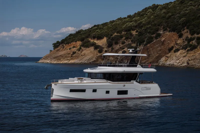 Slide: The Image of 2026 Sirena 60 yacht cruising near rocky coastline under clear skies. - 5