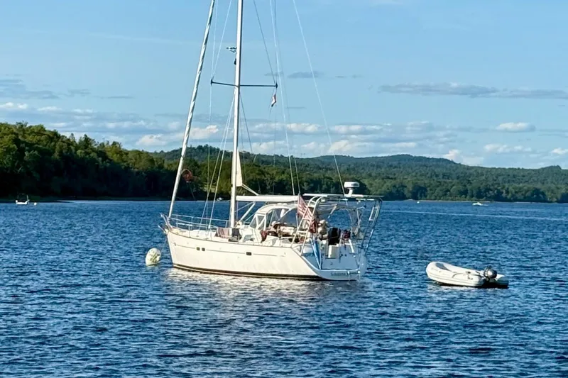 The Image of Sailboat Beneteau 423 (2004) anchored on a serene lake with lush forest backdrop. - 0