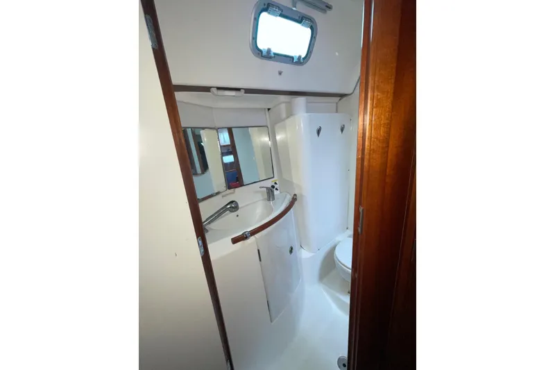 Slide: The Image of Bathroom interior of 2004 Beneteau 423 yacht, featuring sink, mirror, and porthole window. - 13