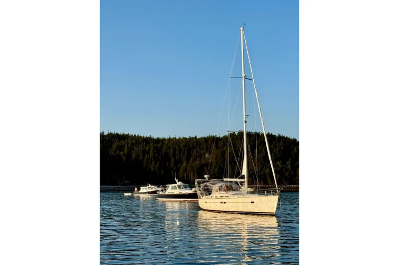 Slide: The Image of Sailboat Beneteau 423 (2004) anchored on calm water with forested background. - 2