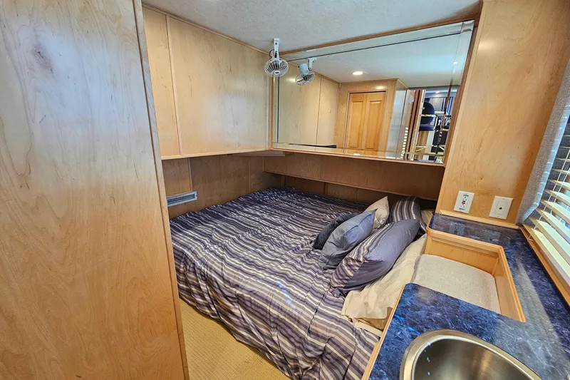 Slide: The Image of Cozy bedroom in 2001 Sumerset 16x79 houseboat with wood paneling and striped bedding. - 21