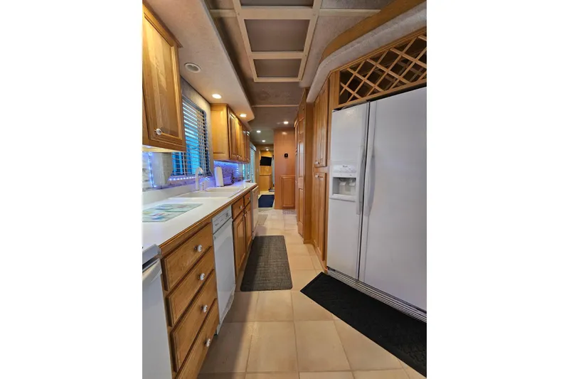 Slide: The Image of Kitchen interior of 2001 Sumerset 16x79 houseboat with wooden cabinets and white appliances. - 23