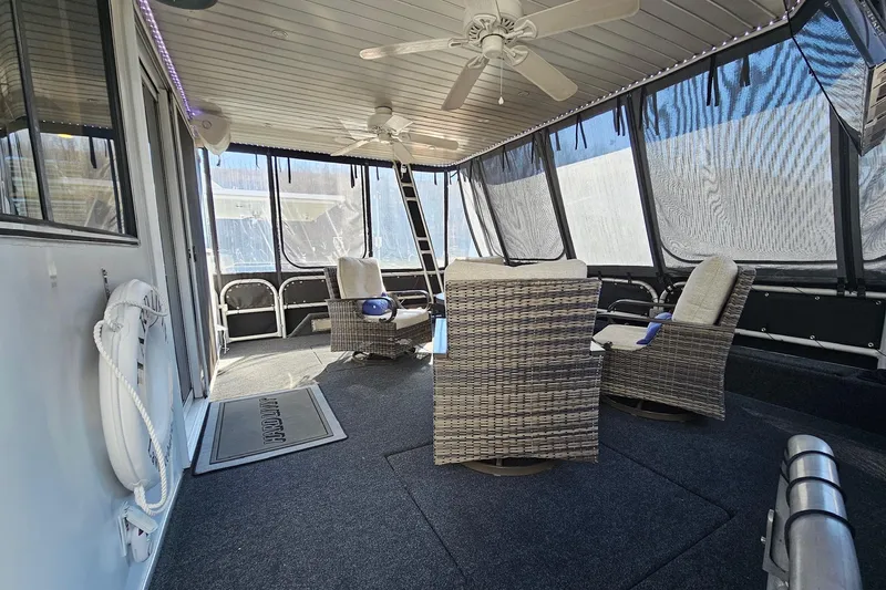 Slide: The Image of 2001 Sumerset 16x79 houseboat interior with wicker chairs and ceiling fans. - 3