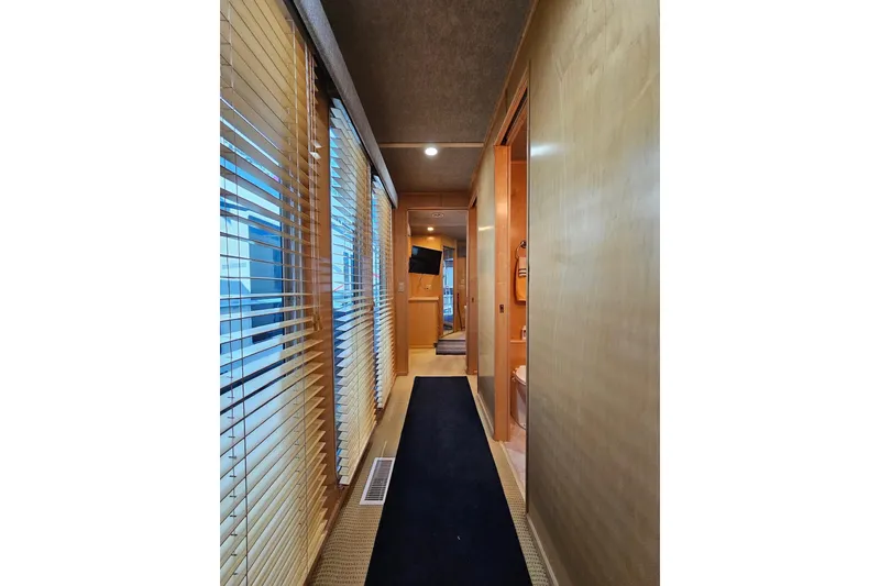 Slide: The Image of Narrow hallway inside 2001 Sumerset 16x79 houseboat with wooden paneling and window blinds. - 31