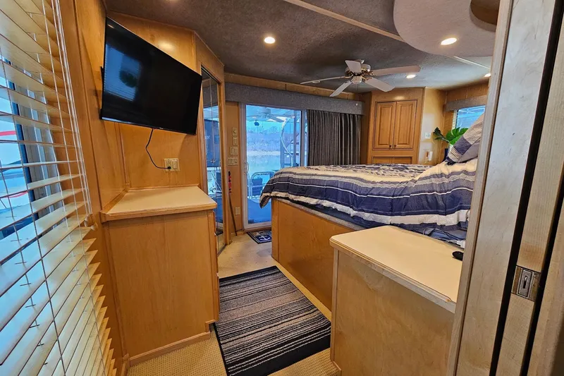 Slide: The Image of Luxurious 2001 Sumerset 16x79 houseboat bedroom with TV, striped bedding, and wood accents. - 38