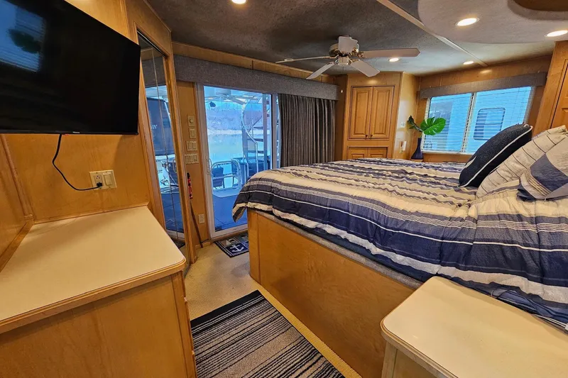Slide: The Image of Luxurious bedroom interior of a 2001 Sumerset 16x79 houseboat with striped bedding and modern amenities. - 39