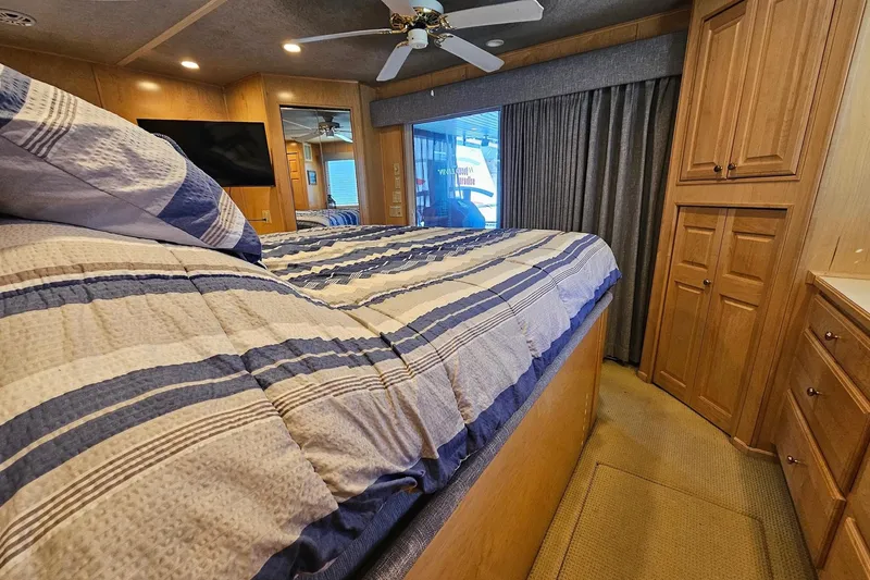 Slide: The Image of Cozy bedroom in 2001 Sumerset 16x79 houseboat with striped bedding and wooden cabinetry. - 42
