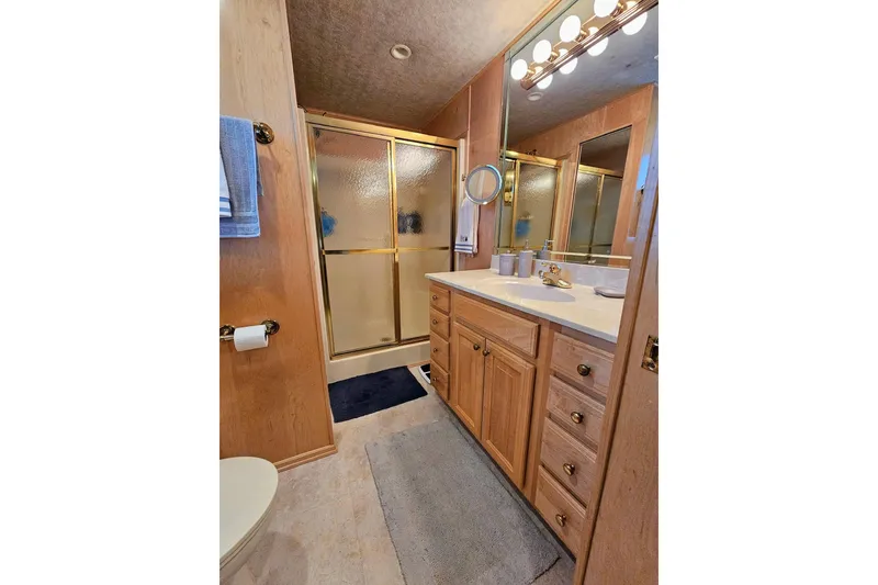 Slide: The Image of Bathroom interior of 2001 Sumerset 16x79 houseboat with wooden cabinetry and glass shower. - 44